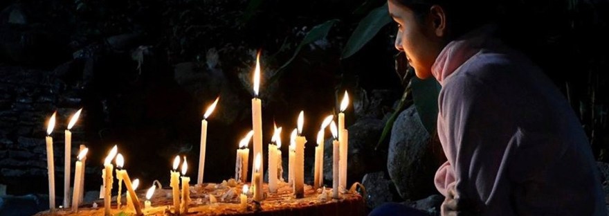 This is an image of a woman praying with candles in an article on Ho'oponopono for dealing with difficult people by Haripriya Suraj, Reiki Master